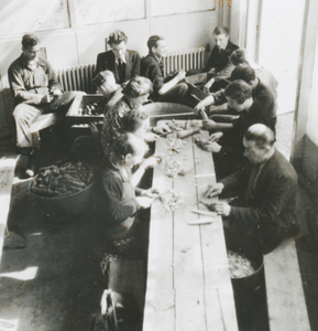 876766 Afbeelding van vermoedelijk vrijwilligers die groenten aan het snijden zijn voor de gaarkeuken in het klooster ...